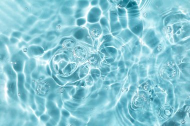 Reflections of the sun, a bunch of bubbles in the wavy water. Blue textured background. Closeup, selective focus, defocus