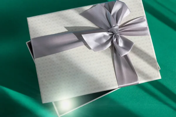 Серый Праздничный Слегка Открытая Подарочная Коробка Луком Зеленом Фоне Солнечном — стоковое фото