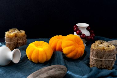 Cadılar Bayramı. Balkabakları koyu bir kumaşın üzerinde yatar, sönmüş mumlar, kırmızı boncuklu sürahiler ve taşlar vardır. Kopyalama alanı olan siyah arkaplan