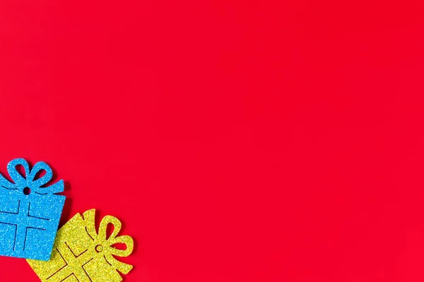 Blue and yellow artificial glittery gifts lie on a red background