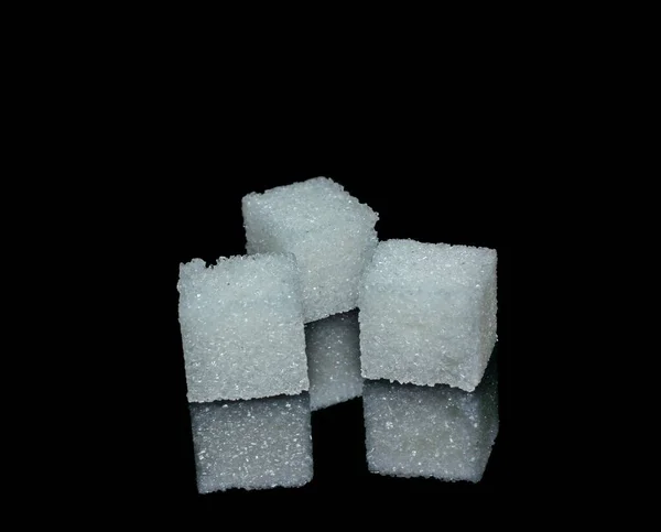 Três cubos de açúcar branco de cristais em vidro preto brilhante — Fotografia de Stock