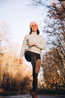 Kız sonbahar ormanında ıssız bir yolda yürüyor. Gülümseyen kız