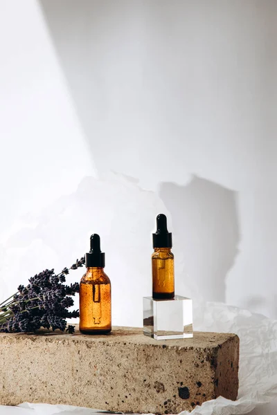 Beyaz arka planda tuğlalardan yapılmış bir kürsüde serum. Serum ve lavanta demeti.