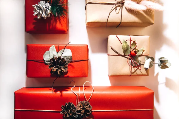 Rote und braune Geschenke mit getrockneten Blumen und Tannenzapfen auf hellem Hintergrund. Flache Lage — Stockfoto