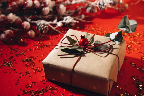 Az ajándék díszített száraz ágak egy piros háttér arany konfetti — Stock Fotó