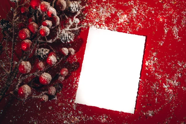 Decorazione natalizia su sfondo rosso. Un ramo di un albero di Natale con bacche rosse su neve con uno spazio di testo — Foto Stock