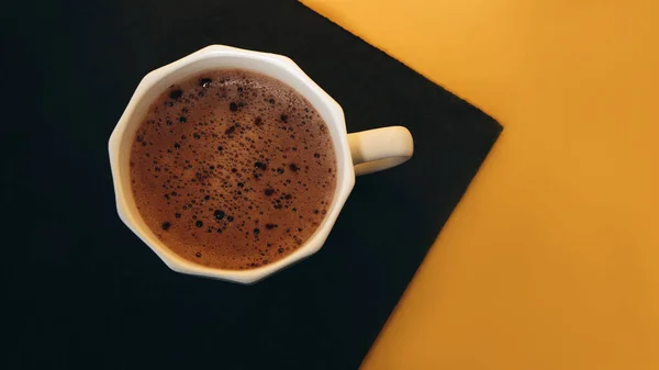Λευκό φλιτζάνι καφέ με αφρό σε μαύρο και κίτρινο φόντο. Μπάνερ — Φωτογραφία Αρχείου