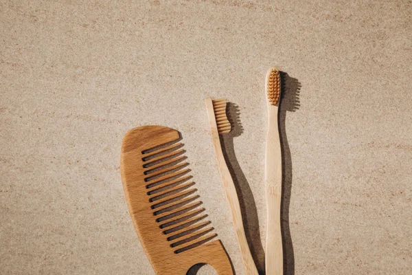 Two wooden toothbrushes and a wooden hairbrush on a light background — Stock fotografie