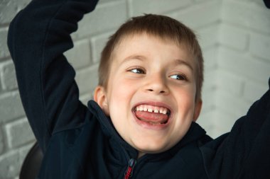 6-7 yaşlarında bir çocuk tatmin olmuş bir yüzle sandalyede oturuyor. Yakından bir çocuğun yüzü.