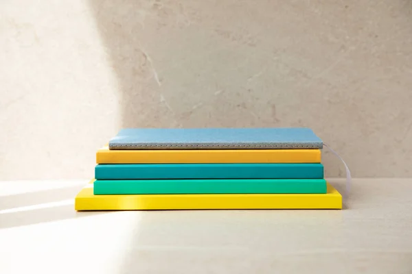 Multi-colored office notebooks on a light beige background, side view of the notebooks