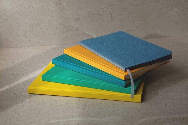 Multi-colored office notebooks on a light beige background. Set of notebooks, front view