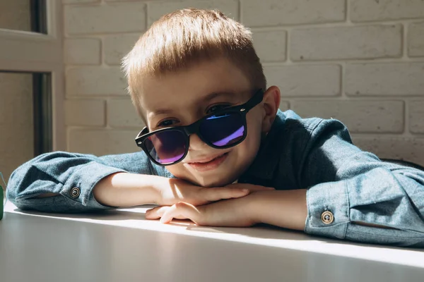 Chlapec Školního Věku Modré Košili Slunečních Brýlích Opře Bílý Stůl — Stock fotografie