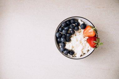 Taze yaban mersini ve bej arkaplanlı bir tabakta çilek. Sağlıklı kahvaltı.