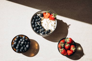Taze yaban mersini ve bej arkaplanlı bir tabakta çilek. Sağlıklı kahvaltı, düz uzanma.