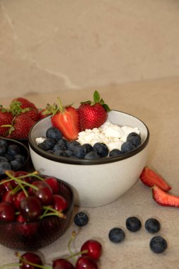 Taze yaban mersini ve bej arkaplanlı bir tabakta çilek. Sağlıklı kahvaltı, ön manzara.