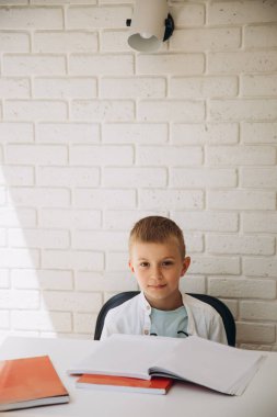 Beyaz tişörtlü beyaz bir çocuk kırmızı ders kitaplarına bakıp gülümsüyor. Okul konseptine dönelim.