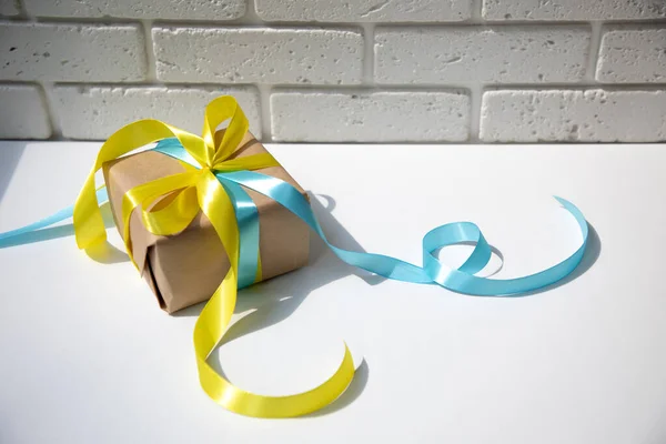 Gift Wrapped Kraft Paper Yellow Blue Ribbon Shadow White Background — стоковое фото