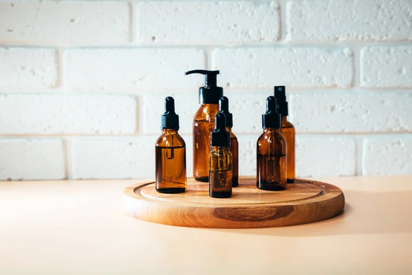 A group of amber bottles on wooden board with face care products. A set of cosmetics in a glass package. Front view