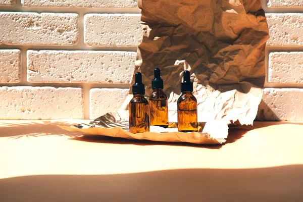 A group of amber bottles on crumpled paper with face care products. A set of cosmetics in a glass package. Front view