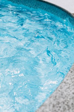 Natural background, water blue waves in the pool with sun reflection