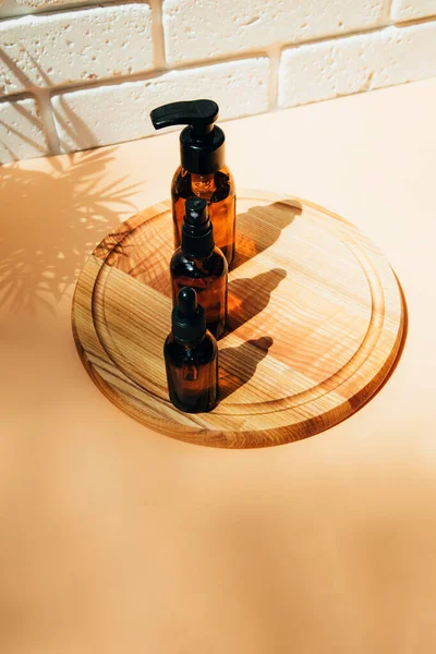 A group of amber bottles on wooden board with face care products. A set of cosmetics in a glass package. Top view