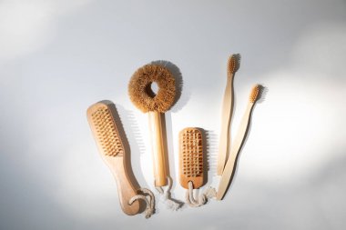 Eco brushes, for nails, washing dishes, toothbrushes with wooden handles on a white background with shadows. Top view