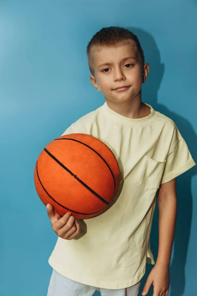 Serious Boy Years Old Yellow Shirt Blue Background Holds Orange — Stock Photo, Image