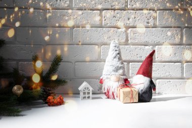 New Year, Christmas background. New Years decor on a white table with branches of a green Christmas tree, pine cones, gnomes. Front view
