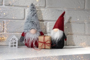 New Year, Christmas background with lights. New Years decor on a white table with gnomes, gift, white house. Front view