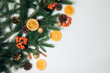 New Year, Christmas background. New Years decor on a white background with branches of a green Christmas tree, pine cones and slices of dry orange. Flat lay