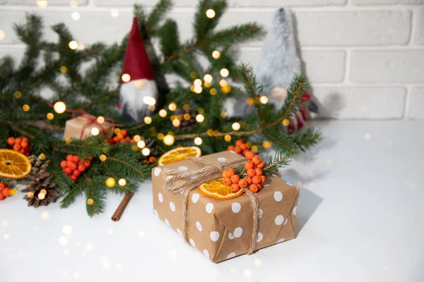 礼物在生态包装 用褐色纸包着白色圆圈 装饰着干橙 山灰和冷杉枝条 新年礼物 白色桌子上的灯 顶视图 — 图库照片