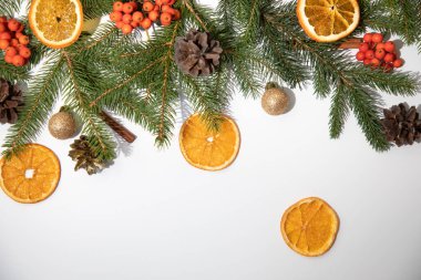 New Year, Christmas background. New Years decor on a white background with branches of a green Christmas tree, pine cones and slices of dry orange. Flat lay