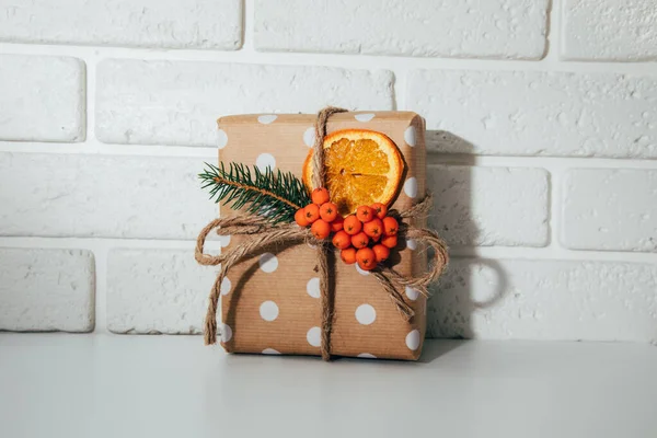 一种环保包装的礼物 用褐色纸包着 装饰有干橙和冷杉枝条 白底新年礼物 — 图库照片