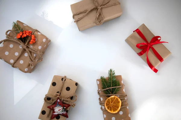 一组生态包装的礼物 装饰有干橙 肉桂棒 红丝带和冷杉枝条 白色背景的新年礼物 — 图库照片
