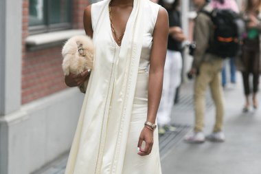 Milan, İtalya - 22 Eylül 2021: Sokak tarzı kıyafet, soluk sarı V yakalı, ipek elbise giyen şık bir kadın, Milan, İtalya sokaklarında bej tüylü bir kürk çanta.