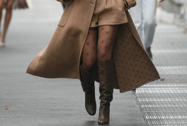 Milan, İtalya - 22 Eylül 2021: Sokak tarzı kıyafet, Fendi 'den altın büyük kolye takan şık bir kadın, Fendi' den altın zincirli bir FF kolye, siyah çizgili kahverengi ve FF monogramlı kesilmiş gömlek, bej balon h