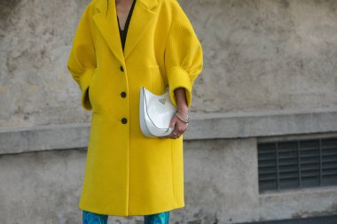 Milan, İtalya - 24 Eylül 2021: Sokak tarzı kıyafet, sarı kurdeleli kadife büyük bir ceket giyen şık kadın, Prada 'dan beyaz deri bir omuz çantası, gümüş bilezikler, gümüş yüzükler, mavi parlak deri topuklu koruyucular, çizme