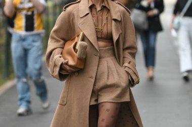 Milan, İtalya - 22 Eylül 2021: Sokak tarzı kıyafet, Fendi 'den altın büyük kolye takan şık bir kadın, Fendi' den altın zincirli bir FF kolye, siyah çizgili kahverengi ve FF monogramlı kesilmiş gömlek, bej balon h