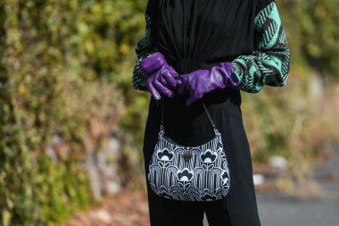 Milan, İtalya - 24 Eylül 2021: Sokak tarzı kıyafet, siyah bir Prada bluz, siyah pantolon, mor uzun eldivenler ve İtalya 'nın Milano sokaklarında Prada çanta giyen şık kadın.