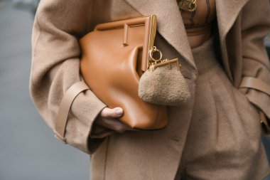 Milan, İtalya - 22 Eylül 2021: Sokak tarzı kıyafet, Fendi 'den altın büyük kolye takan şık bir kadın, Fendi' den altın zincirli bir FF kolye, siyah çizgili kahverengi ve FF monogramlı kesilmiş gömlek, bej balon h