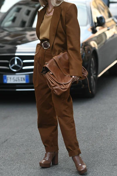 Milan, İtalya - 22 Eylül 2021: Sokak tarzı kıyafet, bej tişört giyen şık kadın, kahverengi ceket, büyük takım elbise pantolon ve Milano, İtalya sokaklarında kahverengi deri bir çanta.