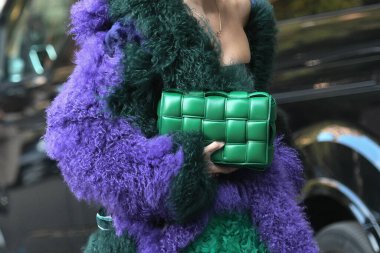Milan, İtalya - 23 Eylül 2021: Sokak tarzı kıyafet, şık bir kadın kırpık tişört giyiyor, Bottega Veneta 'dan yeşil, parlak, deri bir çanta ve İtalya' nın Milano sokaklarında büyük, tüylü bir palto giyiyor..