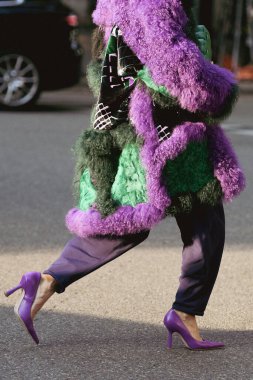 Milan, İtalya - 23 Eylül 2021: Sokak tarzı kıyafet, şık bir kadın kırpık tişört giyiyor, Bottega Veneta 'dan yeşil, parlak, deri bir çanta ve İtalya' nın Milano sokaklarında büyük, tüylü bir palto giyiyor..