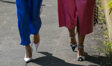Milan, İtalya - 24 Eylül 2021: Sokak tarzı kıyafet, pembe büyük beden ceket giyen iki şık kadın, siyah beyaz Chanel çanta, topuklar ve mavi elbise, beyaz çanta, İtalya, Milano sokaklarında topuklu ayakkabı.