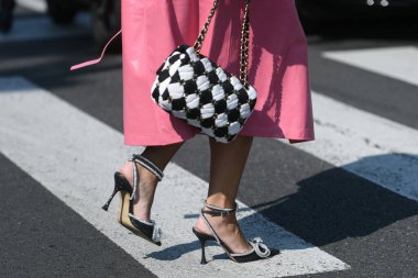 Milan, İtalya - 24 Eylül 2021: Sokak tarzı kıyafet, pembe uzun bir ceket giyen şık kadın, Chanel 'den siyah beyaz bir el çantası, Milan, İtalya sokaklarında gümüş düğümlü elmaslı siyah topuklu ayakkabılar.