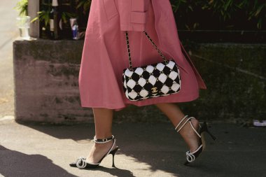Milan, İtalya - 24 Eylül 2021: Sokak tarzı kıyafet, pembe uzun bir ceket giyen şık kadın, Chanel 'den siyah beyaz bir el çantası, Milan, İtalya sokaklarında gümüş düğümlü elmaslı siyah topuklu ayakkabılar.