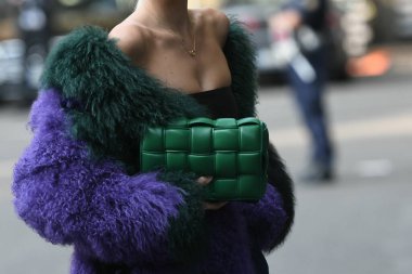 Milan, İtalya - 23 Eylül 2021: Sokak tarzı kıyafet, şık bir kadın kırpık tişört giyiyor, Bottega Veneta 'dan yeşil, parlak, deri bir çanta ve İtalya' nın Milano sokaklarında büyük, tüylü bir palto giyiyor..