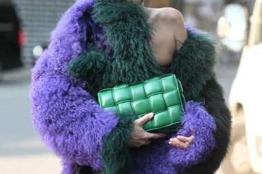 Milan, İtalya - 23 Eylül 2021: Sokak tarzı kıyafet, şık bir kadın kırpık tişört giyiyor, Bottega Veneta 'dan yeşil, parlak, deri bir çanta ve İtalya' nın Milano sokaklarında büyük, tüylü bir palto giyiyor..