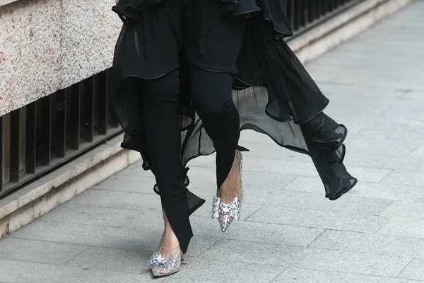 Milan, İtalya - 22 Eylül 2021: Sokak tarzı kıyafet, siyah giysili şık kadın, dar paçalı pantolon, topuklu ayakkabılar Milan, İtalya sokaklarında bir düğüm ile.
