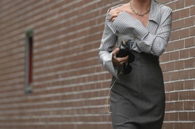 Milan, İtalya - 22 Eylül 2021: Sokak tarzı kıyafet, çizgili bluz giyen şık kadın, gri, mikro çantalı yüksek bel etek, Milano, İtalya sokaklarında güneş gözlüğü.